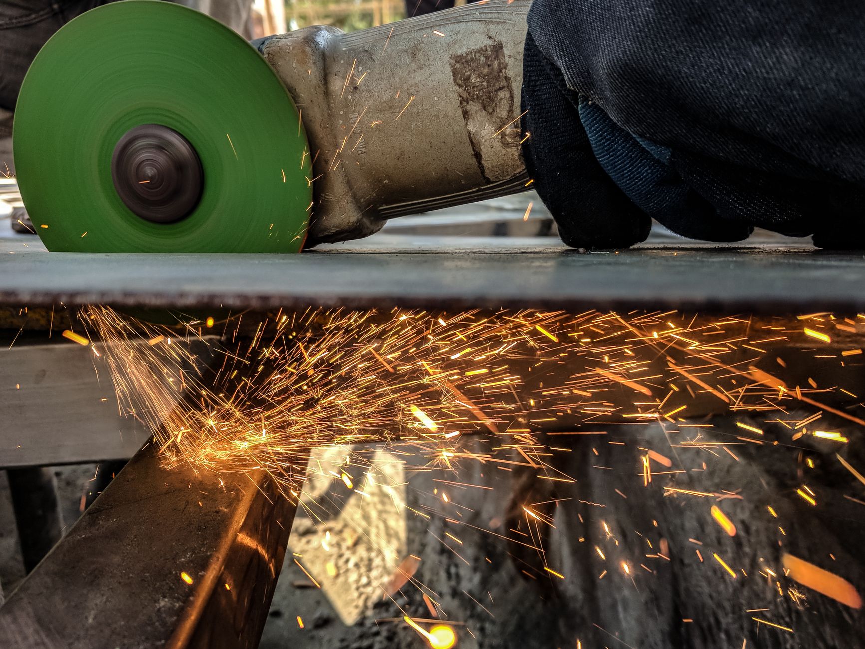 Worker grinding a steel sheet