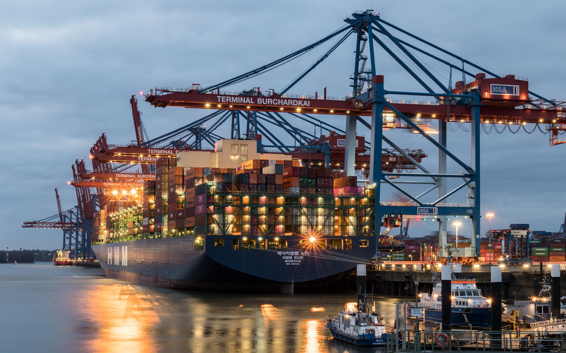 Container ship at a port terminal with cranes at dusk